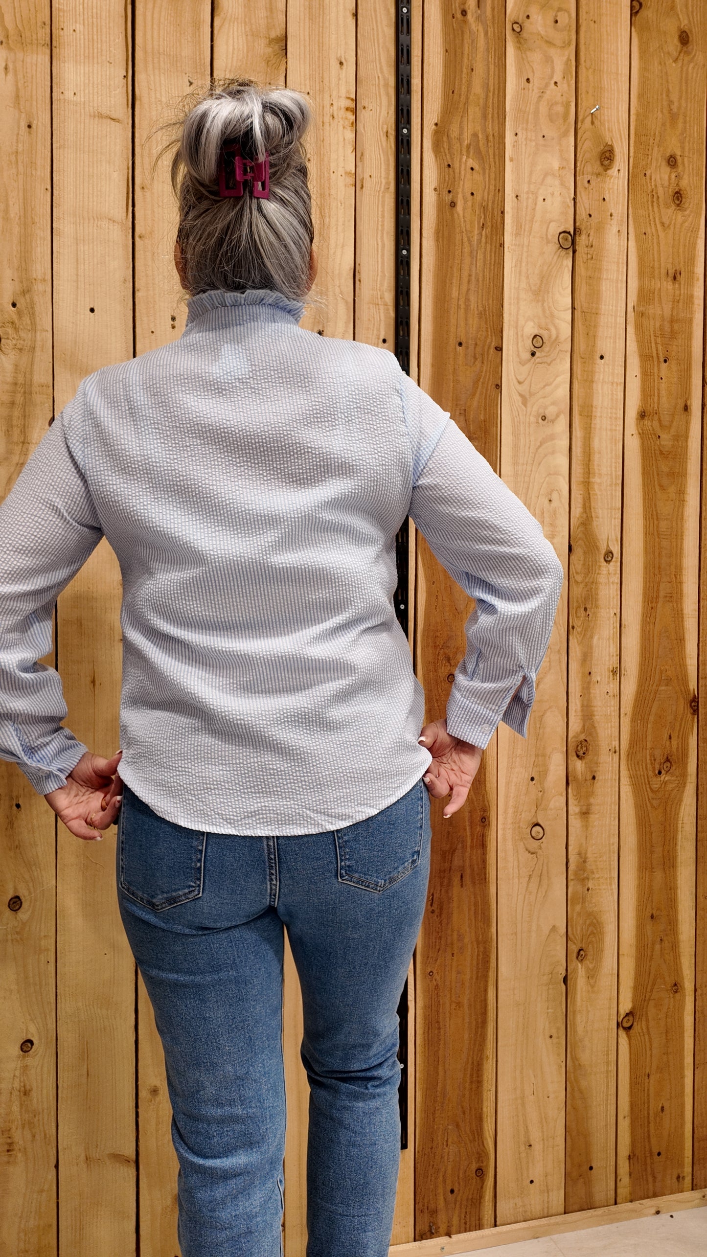 Chemisier bleu élégant avec finition volantée et fermeture boutonnée.