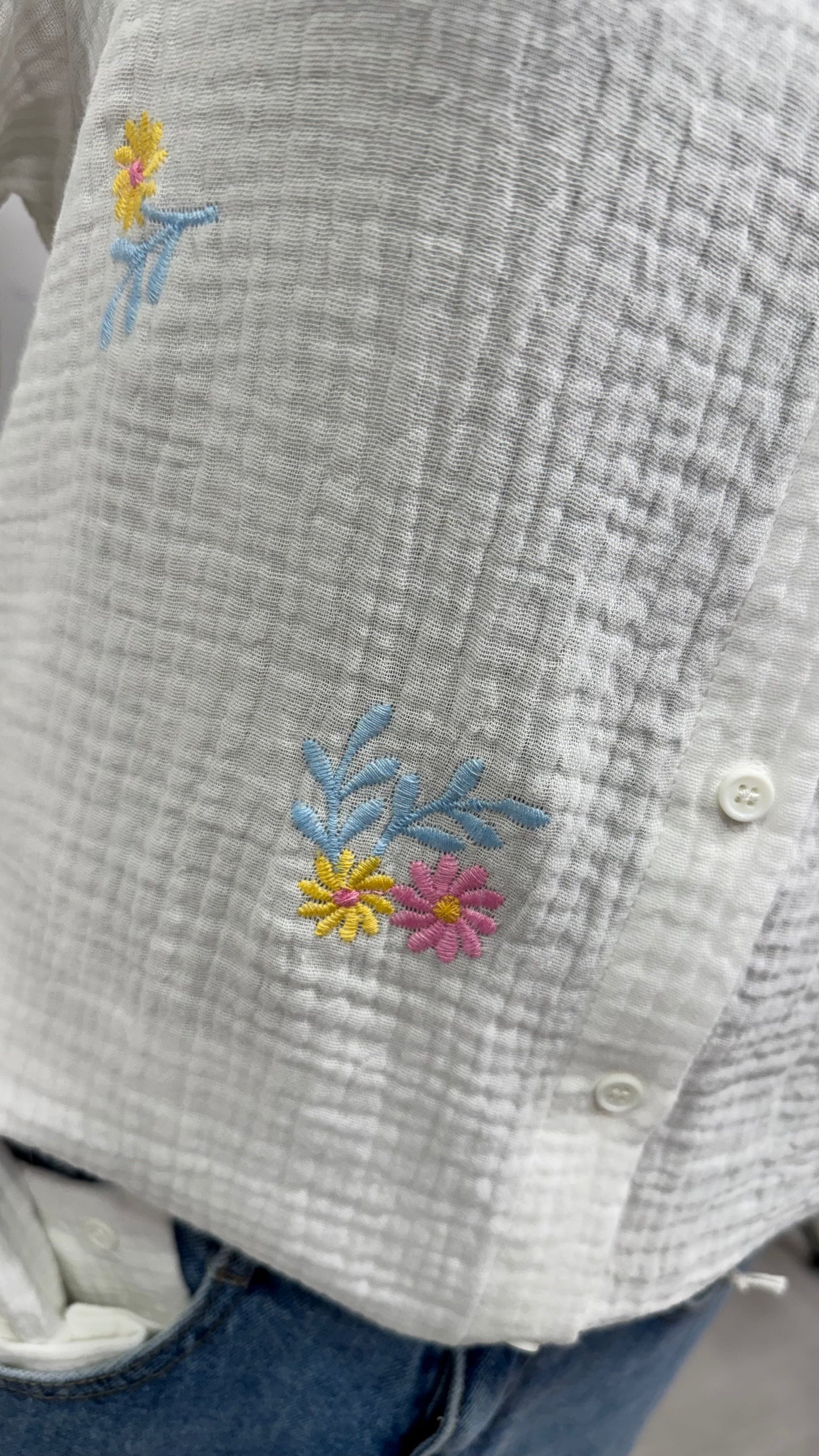 Détail broderie fleurs colorées sur chemisier femme en gaze de coton