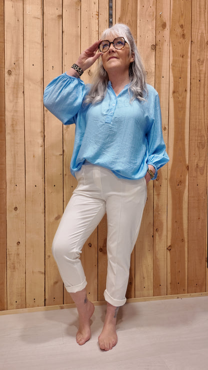 Pantalon de ville blanc femme avec ceinture intégrée, coupe droite ajustée, porté avec blouse bleu ciel– look chic et confortable.
