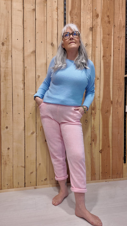 Femme portant un pantalon effet velours rose malabar coupe droite avec revers, associé à un pull bleu ciel.