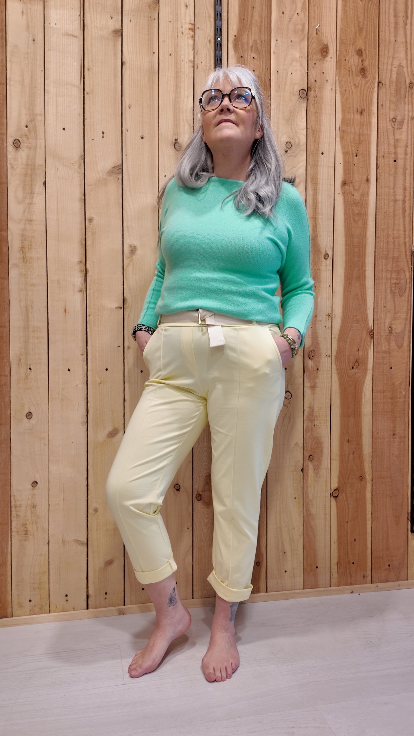 Pantalon de ville jaune femme avec ceinture intégrée, coupe droite ajustée, porté avec pull vert menthe – look chic et confortable.